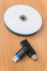 USB flash drives and stacked CDs isolate on wooden background.