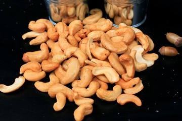 heap cashew nuts and salt on black background