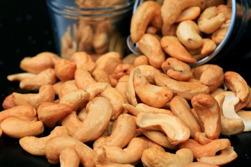 heap cashew nuts and salt on black background