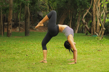Fototapeta premium Young woman doing yoga exercises in the garden park
