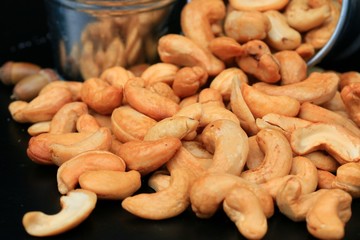 heap cashew nuts and salt on black background