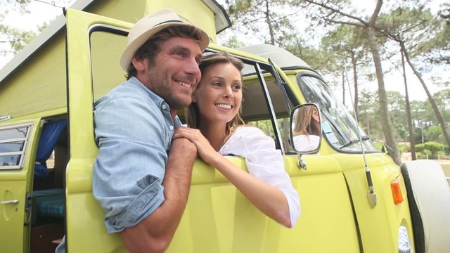 Couple standing by vintage camper van window