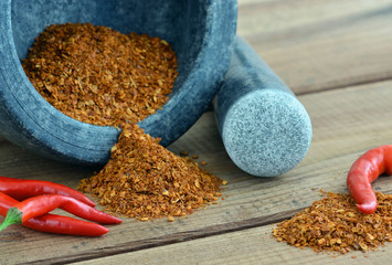 Chilipulver - Chilischoten mit Mörser auf Holztisch
