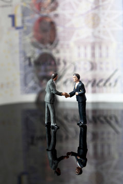 Miniature business figures note sterling.
Miniature scale model business figures standing in front of a twenty pound note sterling.