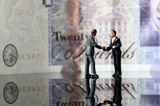 Miniature business figures note sterling.
Miniature scale model business figures standing in front of a twenty pound note sterling.