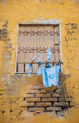 The wall of an old house in Jerusalem, and the Israeli flag
