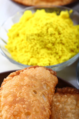 yellow holi colors with gujiya at background