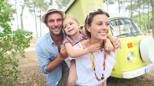 Couple with little girl enjoying vacation in camper van