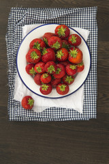 Fresh juicy strawberries on vintage enamelware crockery on rusti
