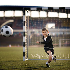 boy plays football on stadium