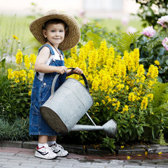 little boy with watering can in summer park