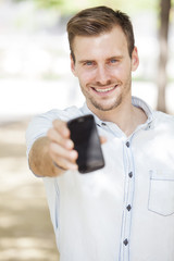 Happy man showing a mobile phone screen outdoor 