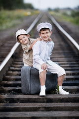 Two boys with suitcase on railways