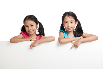 Happy Asian twins girls  behind white blank banner