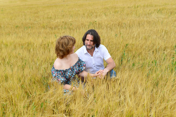 Loving middle-aged couple standing in field in summer