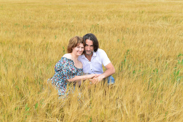 Naklejka na ściany i meble Loving middle-aged couple standing in field in summer