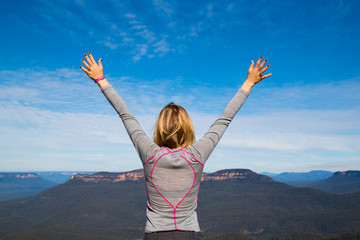 Sporty woman reaching for the sky on a mountain top