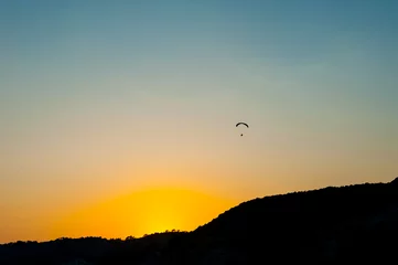 Fototapete Luftsport Gleitschirmfliegen bei Sonnenuntergang