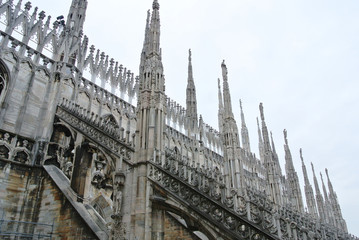 Architectural details from the roof of Milan Cathedral (Duomo di Milano) built in Gothic style, in white marble.