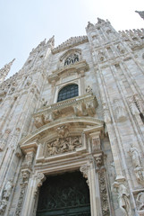 Fototapeta na wymiar Facade of Milan Cathedral (Duomo di MIlano), built in roch Gothic style in white marble. Low angle perspective.