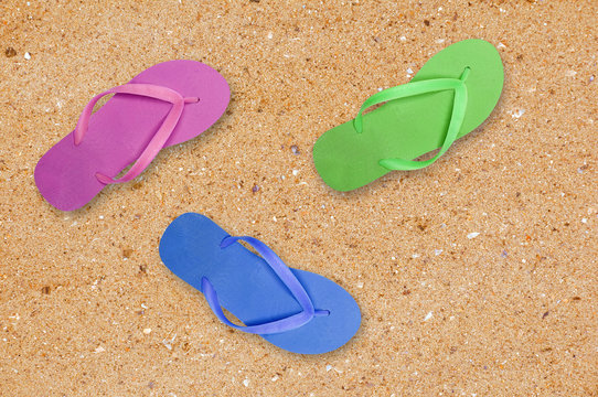 colorful beach shoes over yellow sand background