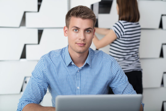 lächelnder junger mann arbeitet am laptop im büro
