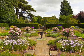 Corner of a flagged English garden with stone vase. 