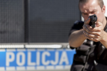 A policeman with a gun on a background the patrol car © Mariusz Niedzwiedzki