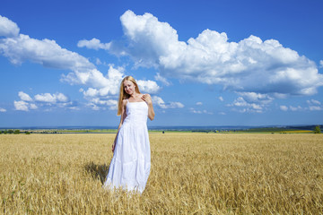 Young beautiful woman in a long white dress is standing in a whe