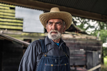 Old farmer standing in front of a rustic barn