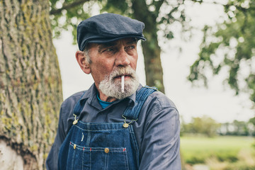 Senior country farmer standing smoking