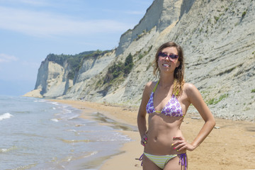 Girl in bikini posing on the beach with rocks in background