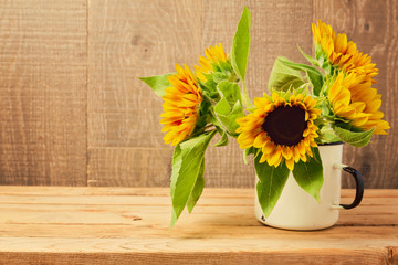 Sunflowers in vintage cup on wooden table. Autumn background