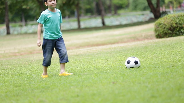 Young asian boy playing soccer in a park, Bangkok Thailand
