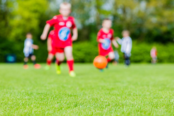 Obraz na płótnie Canvas Blurred kids playing youth football match