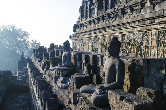 Early morning light shining on Buddhas sitting in the temple complex of Borobodur, Java, Indonesia