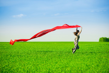Beautiful young woman jumping on a green meadow with colored