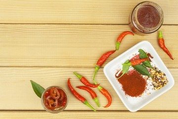 Spices in a ceramic bowl. Freshly picked chili peppers on a wooden table. Preparation for the domestic processing of a crop. Decoration of chilli peppers. Place for text menu. Healthy fresh food.
