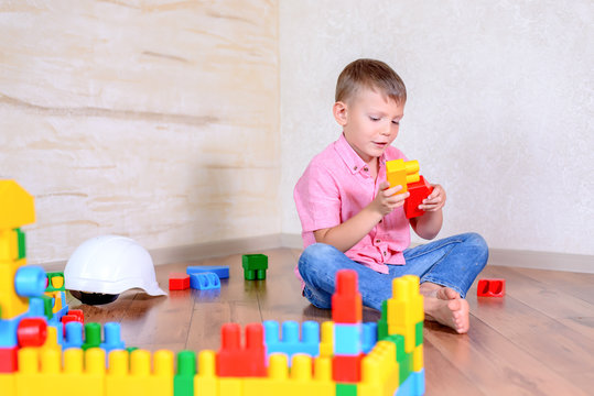 Cute cheeky young boy playing with building blocks