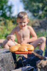 Young boy cooking over a camp fire