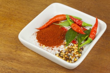 Spices in a ceramic bowl. Freshly picked chili peppers on a wooden table. Preparation for the domestic processing of a crop. Decoration of chilli peppers. Place for text menu. Healthy fresh food.
