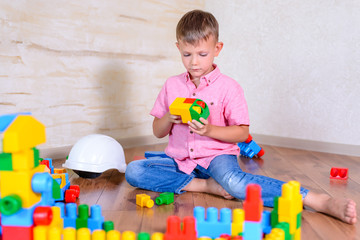 Cute cheeky young boy playing with building blocks