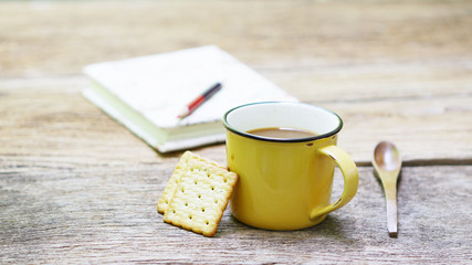 Notebook and tea with cookies on wooden table