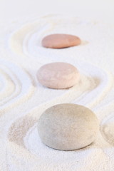 Zen stones on white sand, conceptual image, vertical composition.