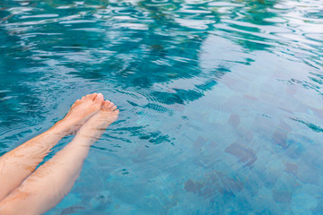 Female legs in the swimming pool water