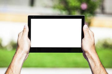 Hands holding tablet with white screen.