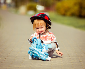 two year old  girl in roller skates and a helmet