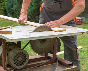 Carpenter working with electric buzz saw cutting wooden boards