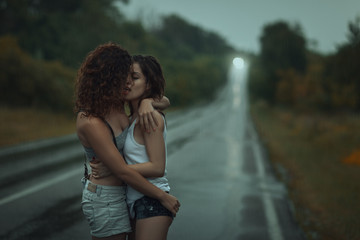Girls lesbians kissing under the heavy rain. - obrazy, fototapety, plakaty