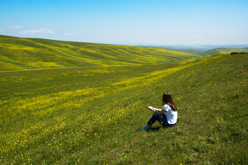 Naklejka na ściany i meble woman sitting and looking at landscape of hills